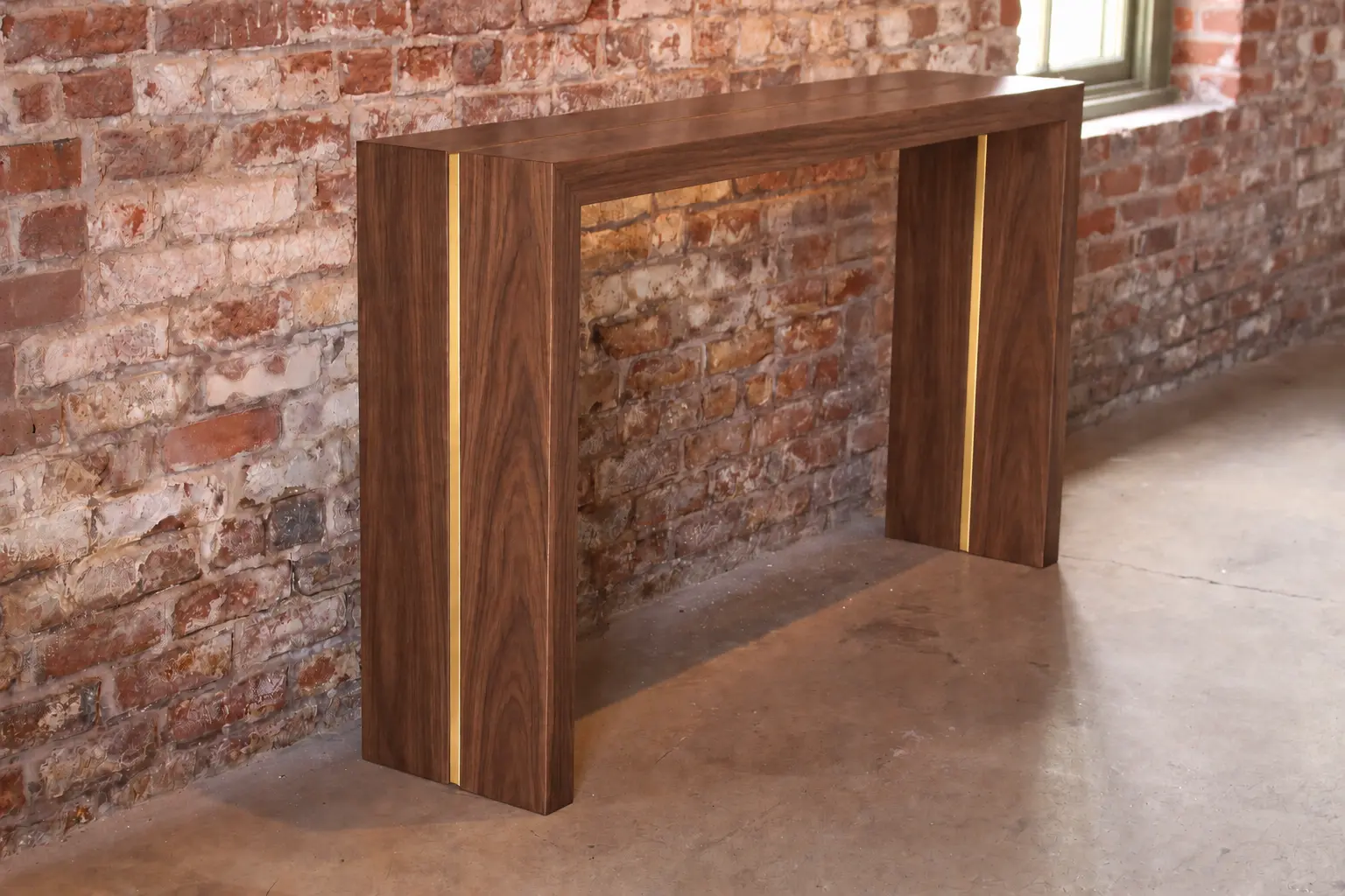 Walnut waterfall console against a brick wall